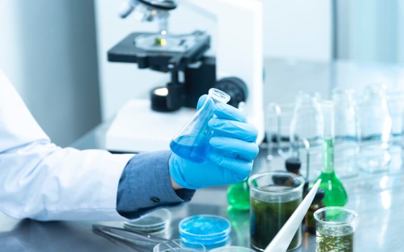 Close-up of a chemist's hand holding a vial
