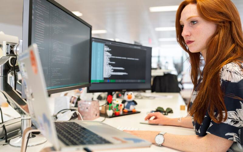 Lady coding at three screens