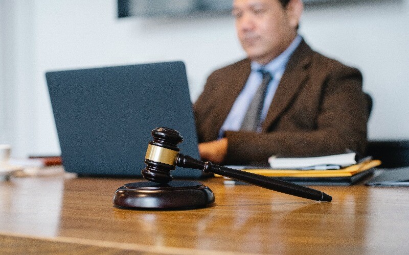 Businessman in a suit working on a laptop with a gavel on desk